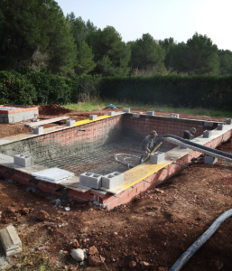 Workers putting in heavy coating of gunite around the rebar for the new pool.